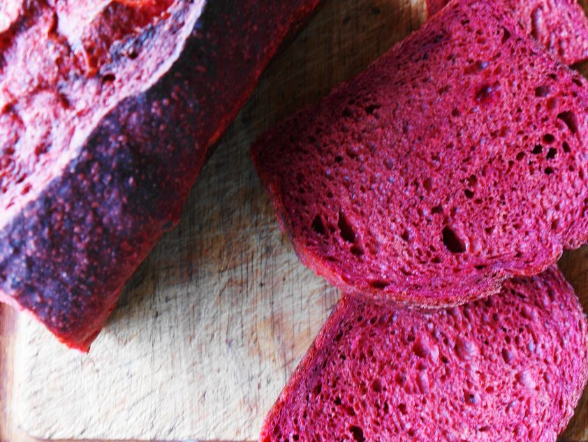 Bright pink homemade beetroot bread loaf cooling on a wire rack