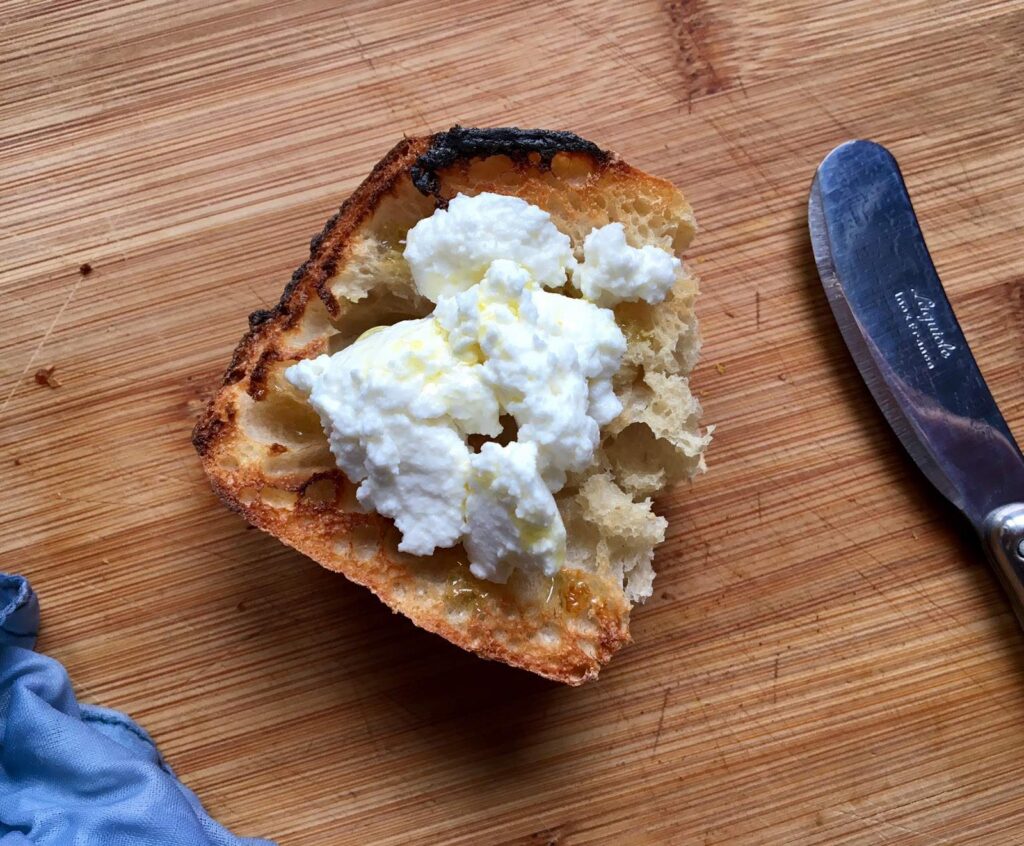 Creamy fresh goats’ curd spread on toasted baguette with olive oil