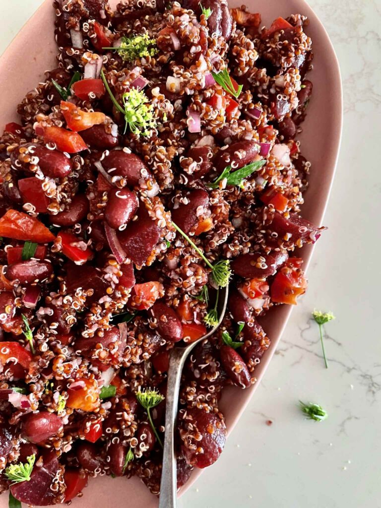 Red quinoa salad with baby beetroot, kidney beans, red capsicum and fresh herbs on a serving platter