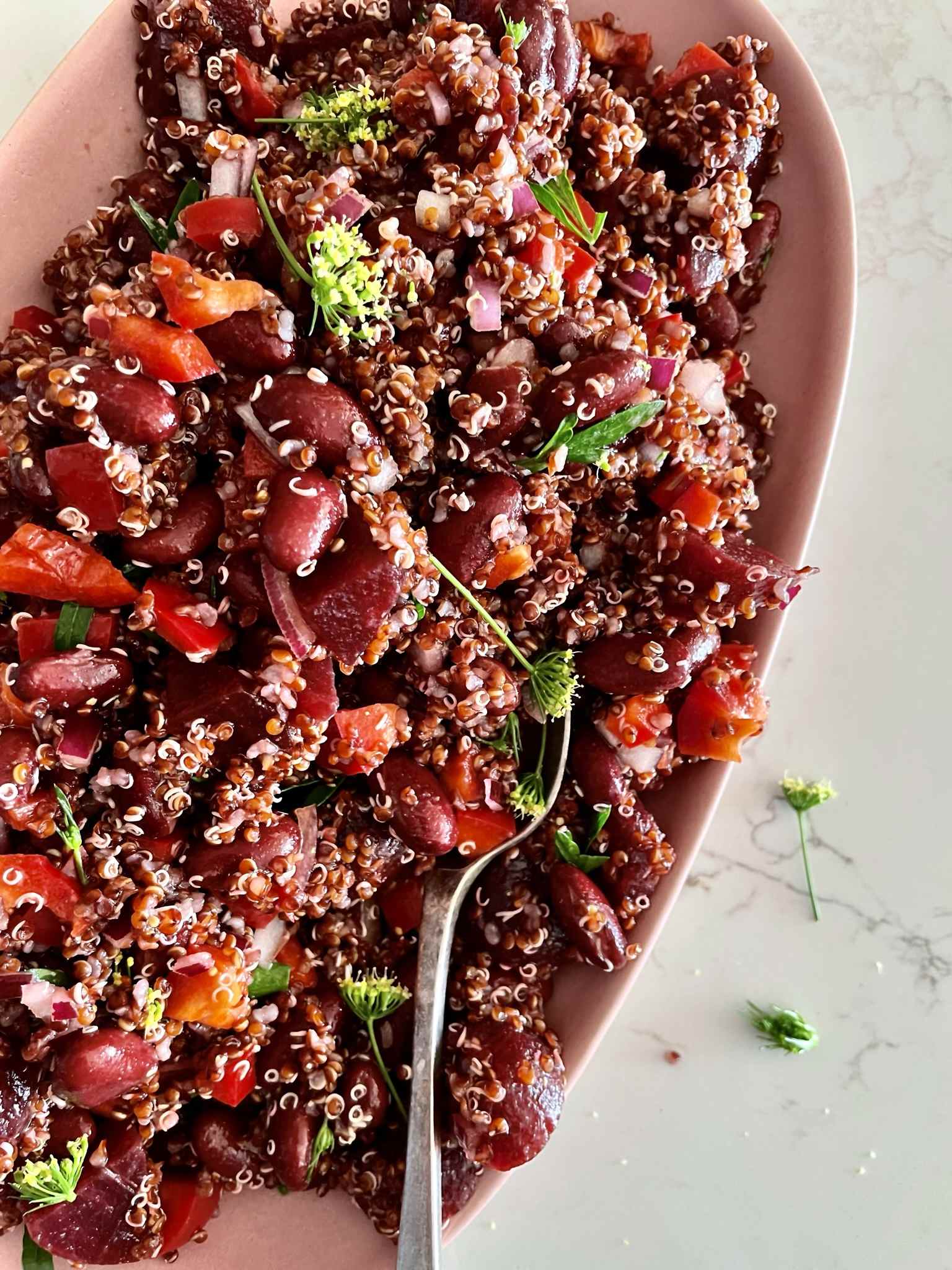 Red quinoa salad with baby beetroot, kidney beans, red capsicum and fresh herbs on a serving platter